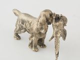 a silver figurine of two dogs with a bird in its mouth