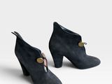 une paire de bottines en daim noir ornées de boutons dorés