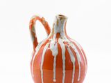 a small orange vase with a white stripe on it