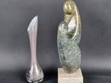 a statue of a woman sitting on a rock next to a vase
