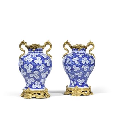 paire de vases bleus et blancs avec des anses dorées, posés sur des socles