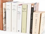 several books are stacked on top of each other on a white surface