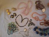 many different necklaces and bracelets laid out on a table