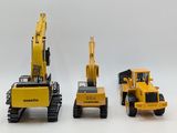 three toy construction vehicles that are lined up on a white surface