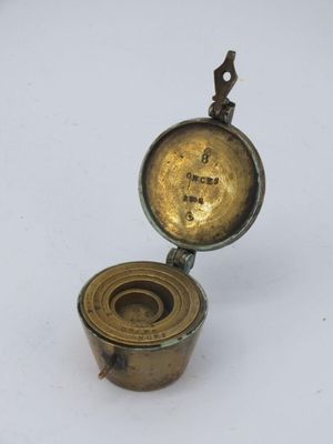 an antique brass compass with a brass case on a white surface