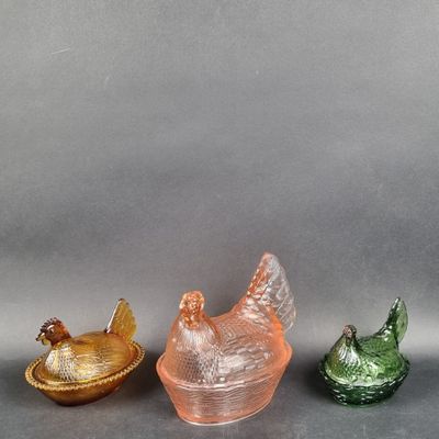 trois figurines en verre de couleurs différentes posées sur une surface grise