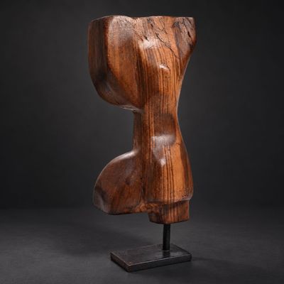 a wooden sculpture of a female torso on a black background