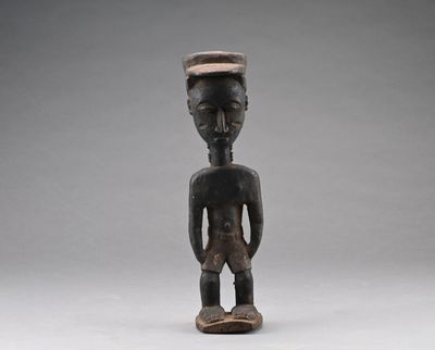 une vieille figurine en bois représentant un homme avec un chapeau sur la tête