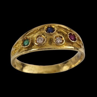 un gros plan d'une bague en or sertie de pierres de différentes couleurs