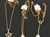 three gold necklaces with charms and a star on a chain