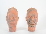 paire de vases en terre cuite rouge représentant des têtes aux yeux fermés sur fond blanc