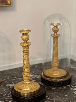 trois bougies posées sur une table sous une cloche en verre
