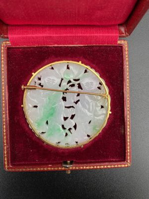 an image of a white and green broochle in a red box