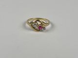 un gros plan d'une bague en or sertie d'une pierre rose et blanche