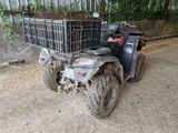 a black atv with a basket on it parked in front of a fence