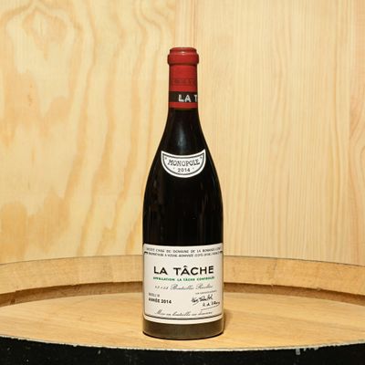 a bottle of wine sitting on top of a wooden barrel