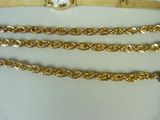 three gold chains and a watch on a white surface