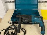 une perceuse et un cordon rangés dans un étui posé sur une table