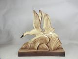 a ceramic sculpture of two birds flying over a wave