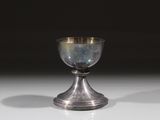 un gobelet en argent posé sur une table, sur fond noir