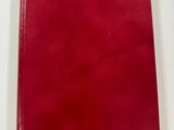 a red book sitting on top of a white table next to a pen