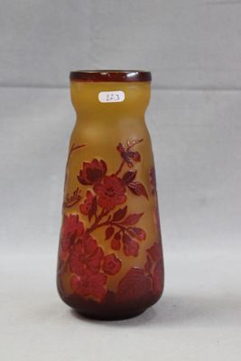 un vase en verre orné de fleurs rouges, posé sur une surface blanche