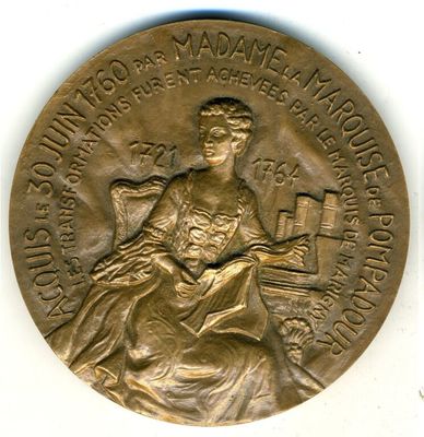 La médaille est en or et représente une femme assise sur une chaise.