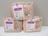 three packs of baby diapers sitting on top of a white table