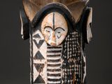 a close up of a wooden vase with a face on it
