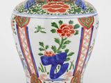 un vase orné d'un motif floral sur une surface blanche