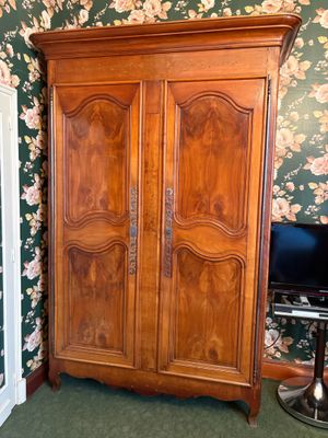 une armoire en bois dans une pièce au papier peint à motifs floraux