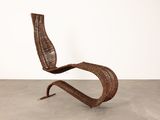 a brown wicker chair sitting on top of a cement floor