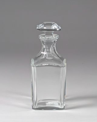 une bouteille en verre transparent avec un bouchon transparent, posée sur une surface blanche