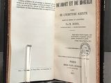 a book open on a table next to a pair of candles