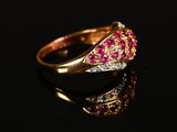 a close up of a gold ring with pink stones on a black surface