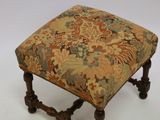 an antique foot stool with a floral upholstered seat
