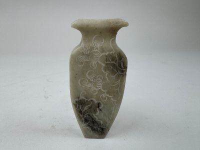 un vase blanc orné d'un motif posé sur une table