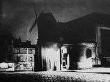 photo nocturne d'une rue avec un immeuble et un clocher
