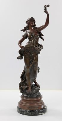 une statue en bronze d'une femme tenant un oiseau sur un piédestal