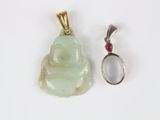 un petit pendentif en forme de Bouddha et une bague posés l'un à côté de l'autre