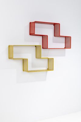 three shelves on the wall that are painted red, yellow, and white