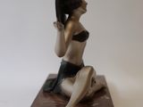 a figurine of a woman in a bikini sitting on a marble block