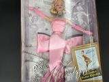 barbie doll in a pink dress in a box on a black surface