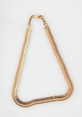 a close up of a gold necklace on a white surface