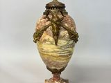 a vase with a statue on top of it on a table