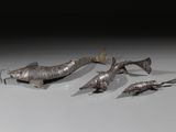 plusieurs poissons en métal posés sur une surface blanche avec un fond noir