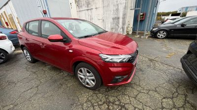 une voiture rouge garée dans un parking à côté d'autres voitures