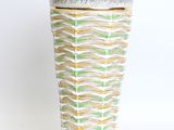 a white vase with a green and yellow design on it