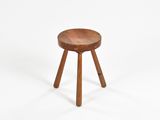 un petit tabouret en bois posé sur une surface blanche