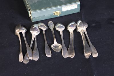 six cuillères et une boîte de couverts posés sur une table